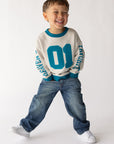 Child modeling the oversized Heaven’s Favorite kids crewneck sweatshirt with jeans and white sneakers