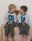 Two children modeling Heaven’s Favorite kids crewneck sweatshirts with teal 01 appliqués