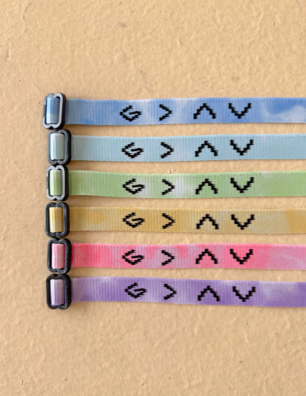 Six Highs and Lows tie-dye bracelets arranged flat, showing assorted colors and adjustable closures