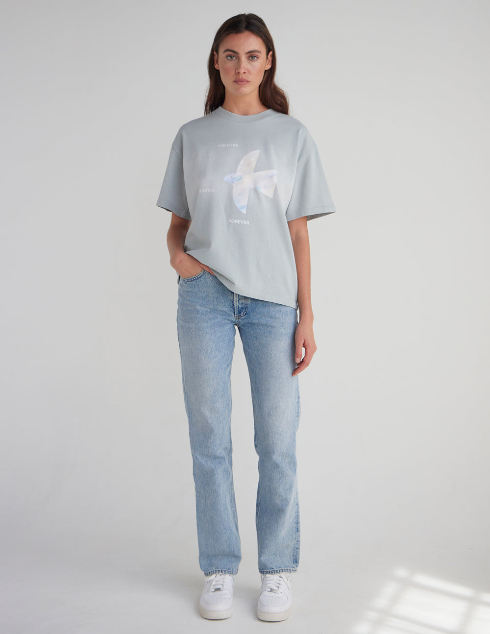 Model wearing the His Love Endures Forever Pearl Blue heavyweight tee with light blue jeans