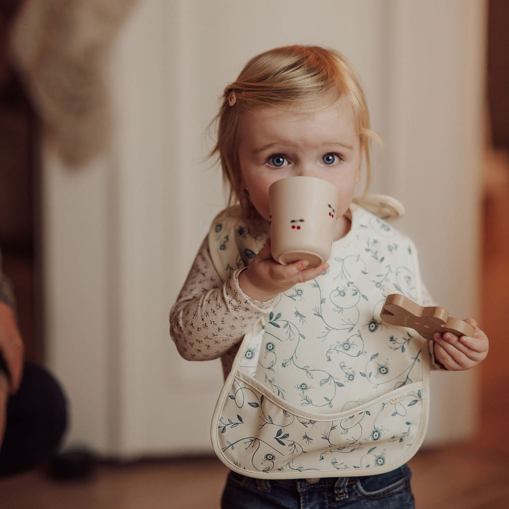 Child drinking from a mug with a neutral background