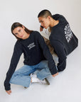 Two models wearing black Chicago long sleeve tees, showing the front lettering and back graphic