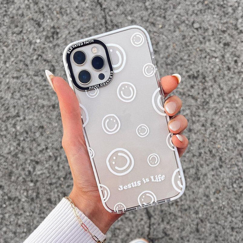 Clear phone case with smiley face pattern held by a person on a textured surface