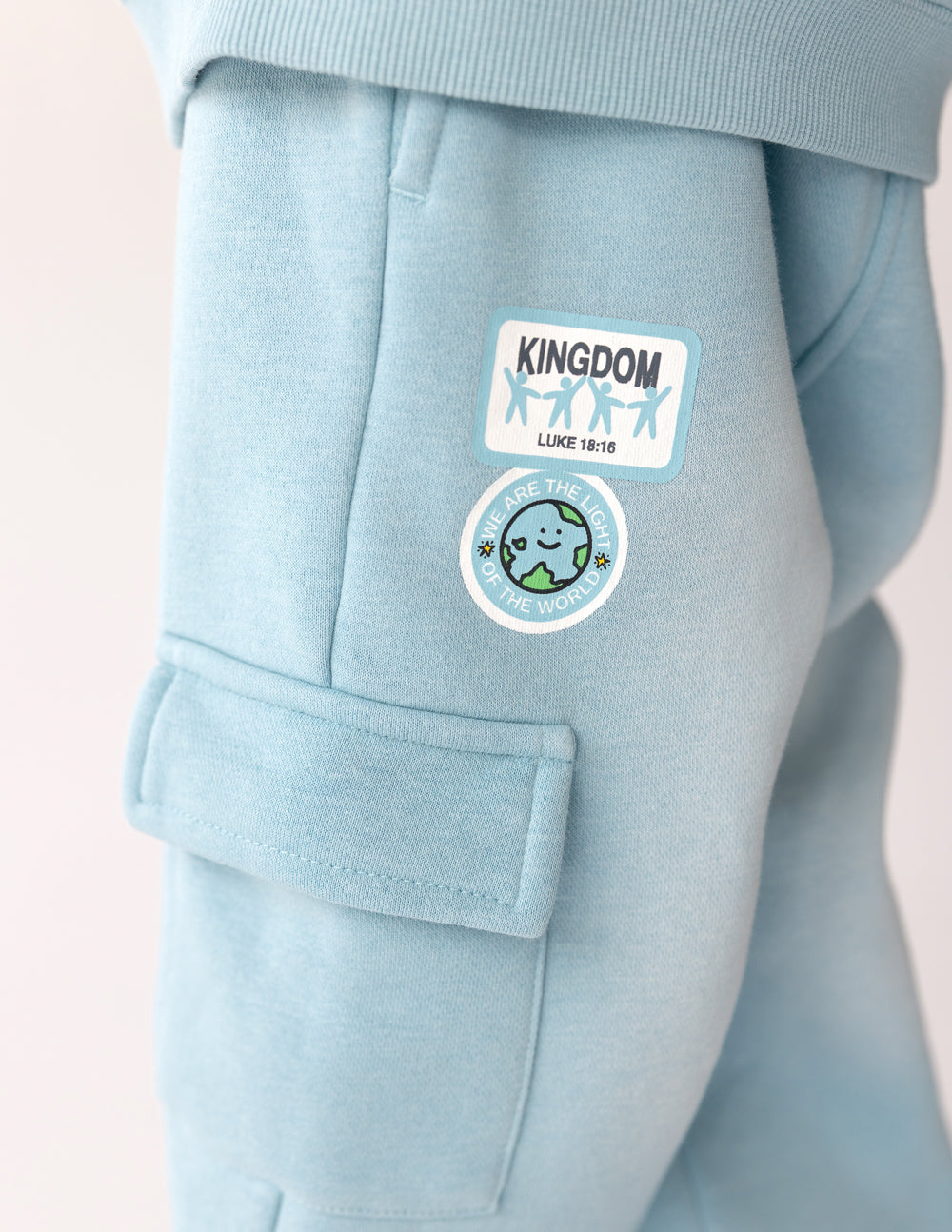 Close-up of cargo pocket and Kingdom Kids graphics on Air Blue sweatpants