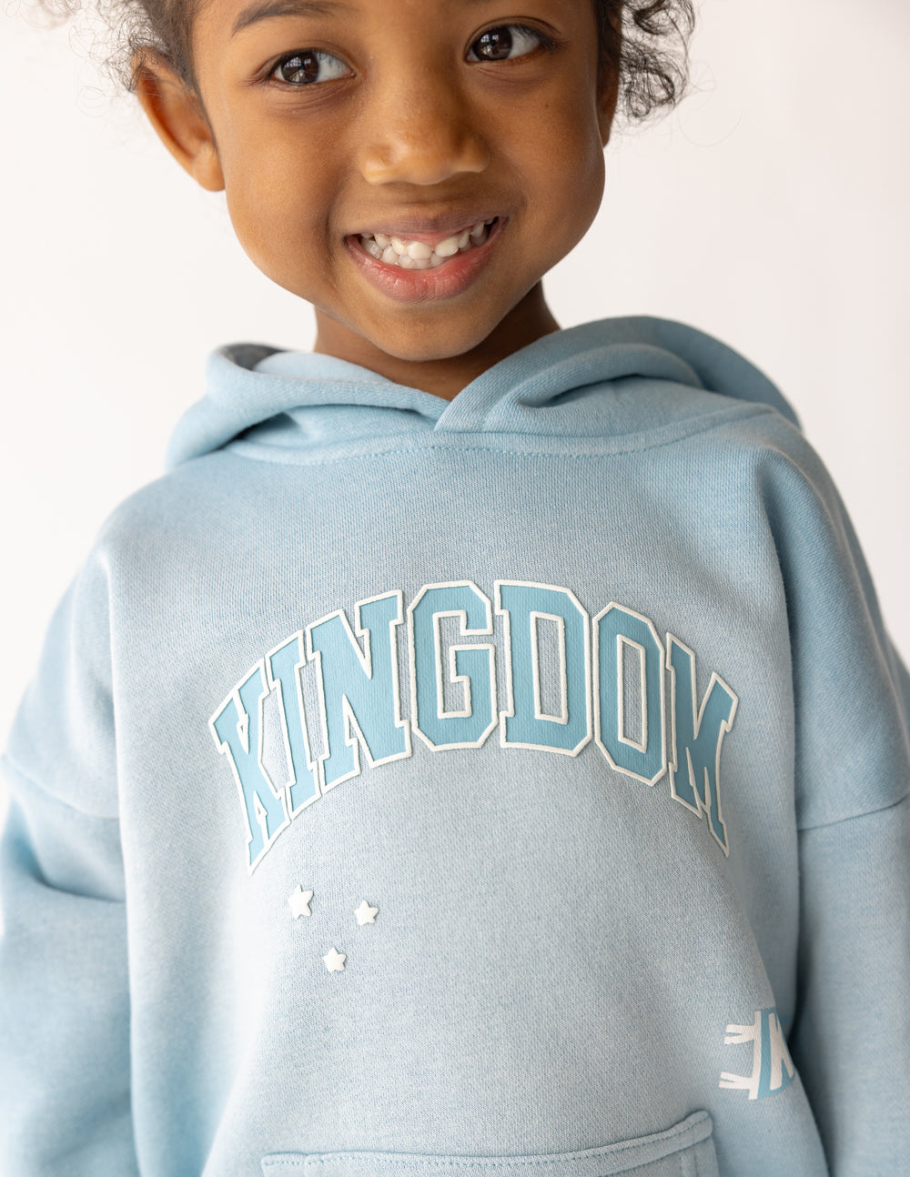 Close-up of the Air Blue Kingdom Kids Hoodie showing puff-print Kingdom lettering