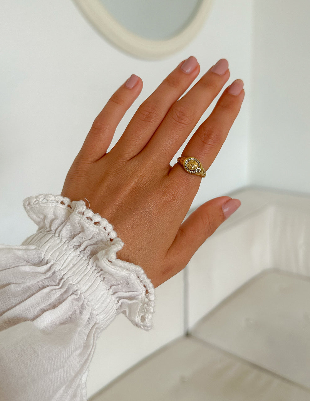Hand wearing the Kingdom cross signet ring beside a white ruffled sleeve.