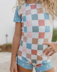 Child wearing a checkered swimsuit with a blurred beach background
