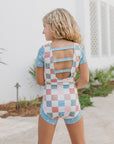 Person wearing a colorful checkered romper with cut-out back design.