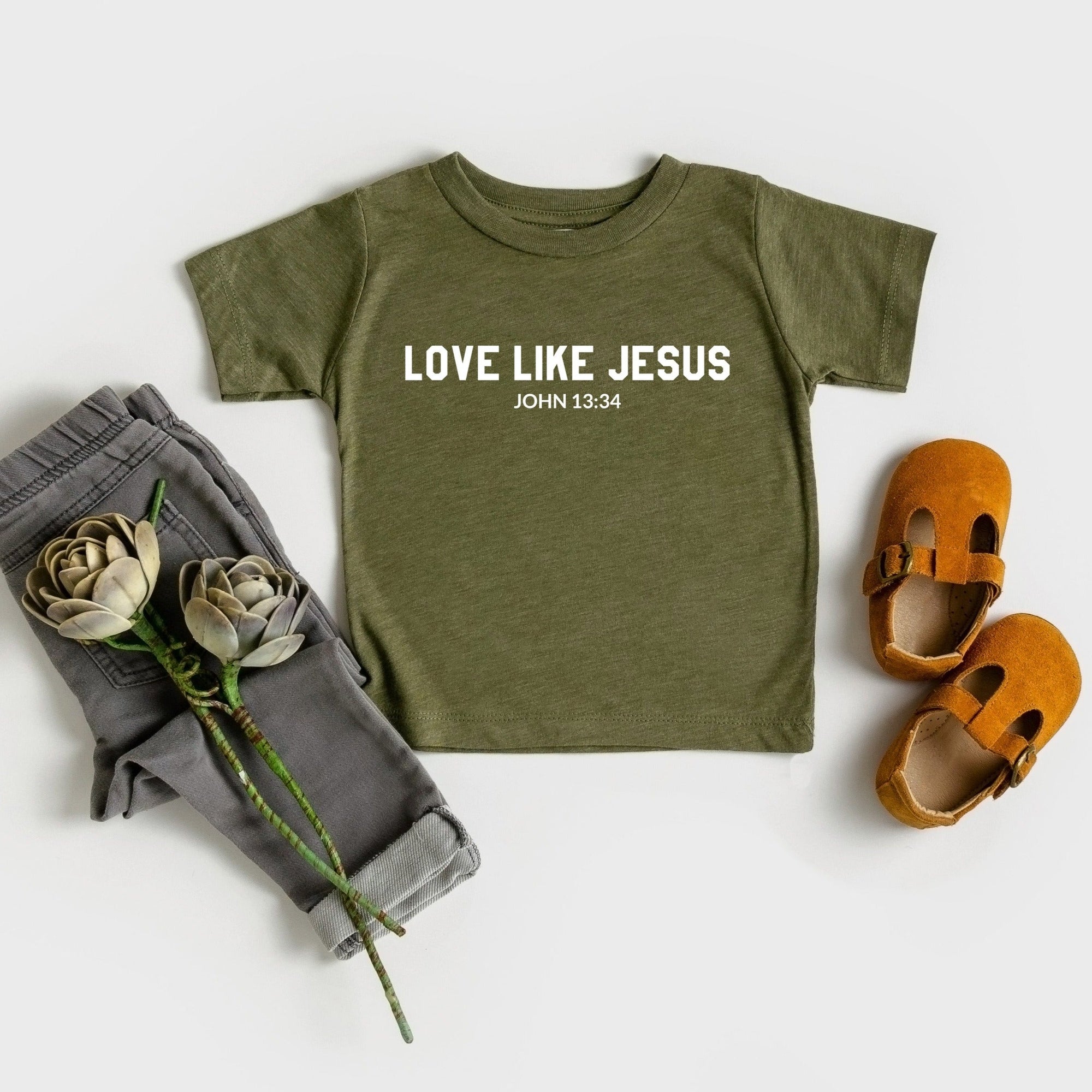 Green t-shirt with 'Love Like Jesus' text, gray pants, and brown shoes on a white background