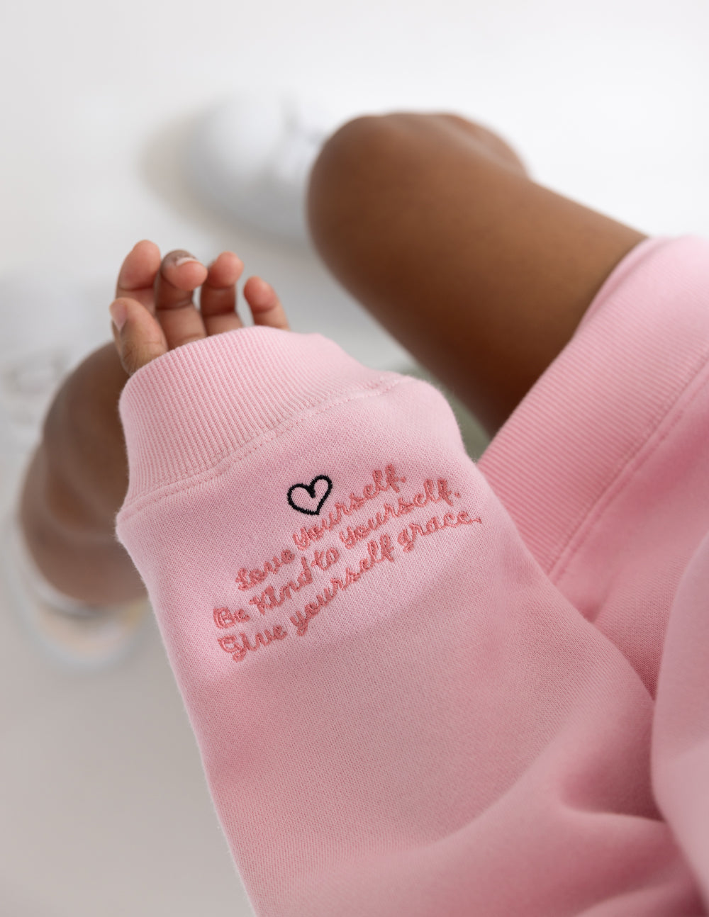 Close-up of the pink sweatshirt sleeve showing encouraging lettering and a small heart.