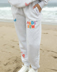 Person wearing gray sweatpants with colorful text on a beach