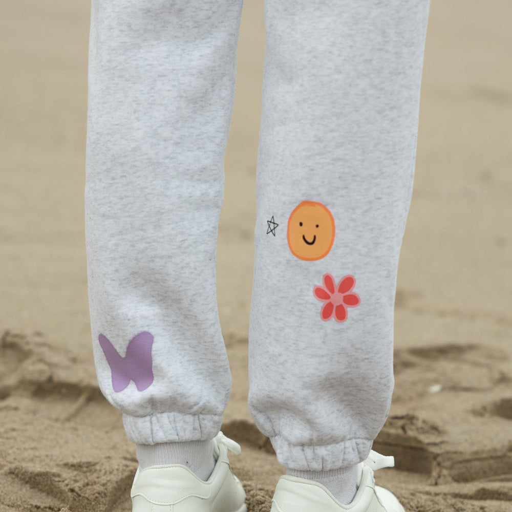 Gray sweatpants with colorful designs on a sandy background