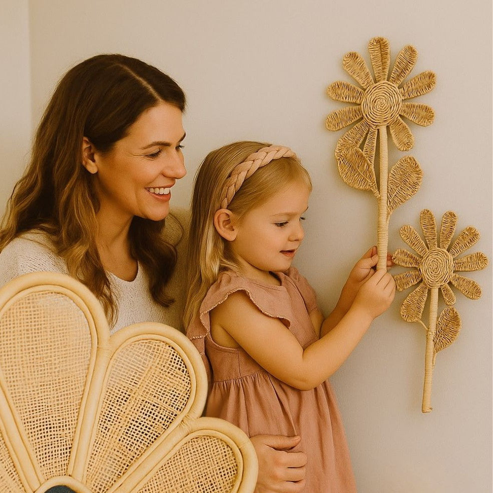 Woman and young girl interacting with decorative rattan flowers in a home setting