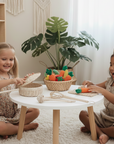 Two young girls playing with toys in a room with a white table and plants.