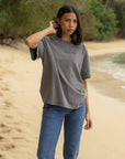 Woman wearing a boxy grey Not Sorry Jesus Is King heavyweight tee with blue jeans outdoors