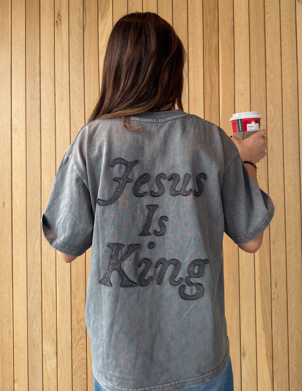 Back view of grey Jesus Is King appliqué tee worn indoors