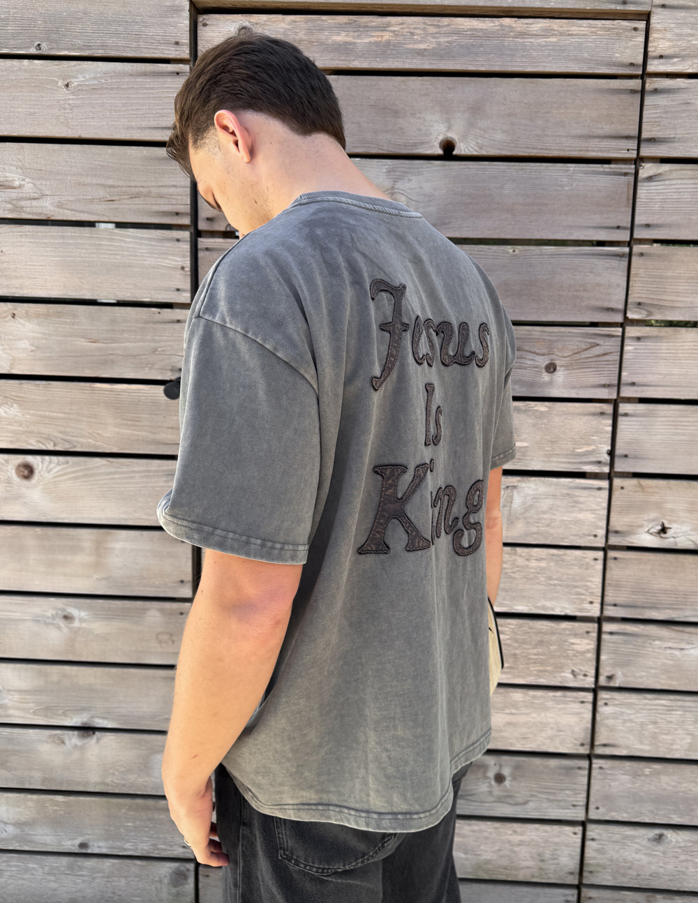 Man wearing grey Jesus Is King heavyweight tee showing the oversized back lettering