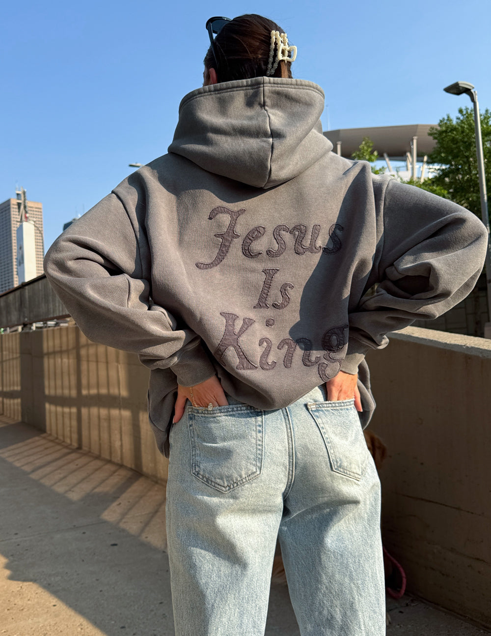 Model wearing the Jesus Is King grey hoodie with light jeans, showing the back appliqué