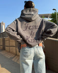 Model wearing the Jesus Is King grey hoodie with light jeans, showing the back appliqué
