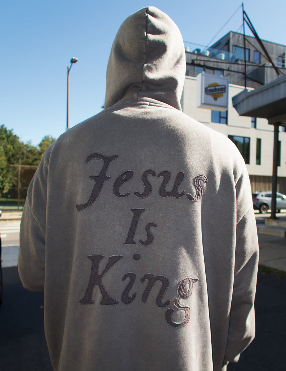 Back view of the Spire Grey hoodie with the hood raised and oversized tonal Jesus Is King lettering
