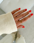 Open Cross Gold-Tone Ring worn on a hand with coral nails and a cream sleeve indoors