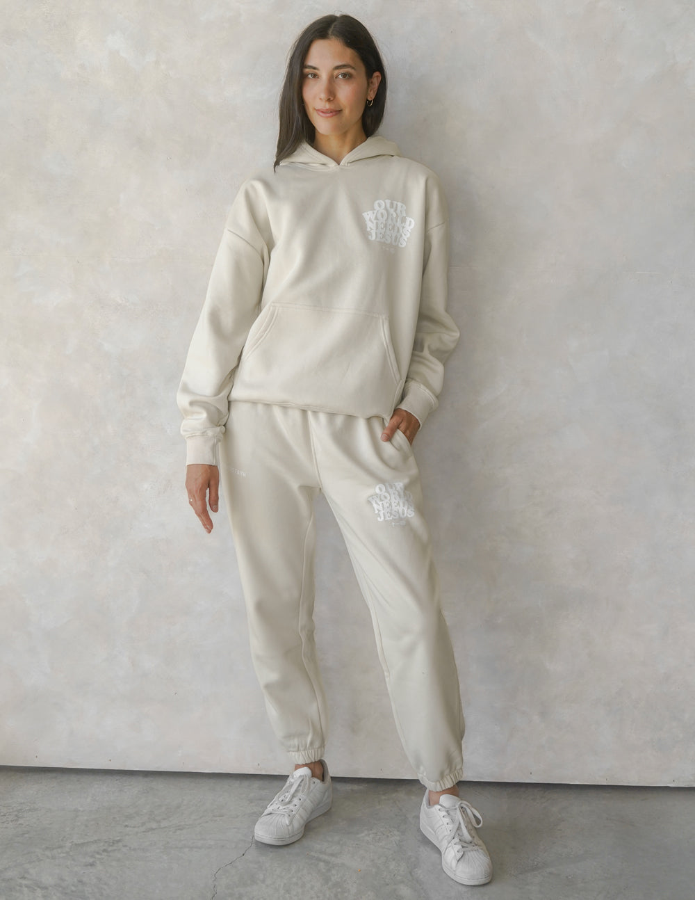 Person wearing a beige tracksuit with a logo against a plain background