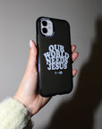 Hand holding a dark Our World Needs Jesus iPhone case against a softly lit wall