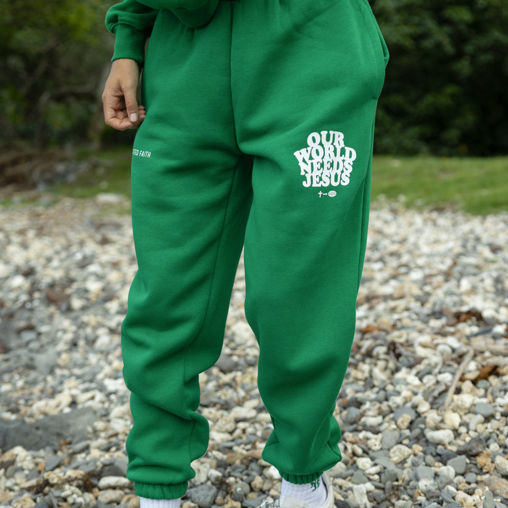 Person wearing green sweatpants with text, standing on a gravel surface.