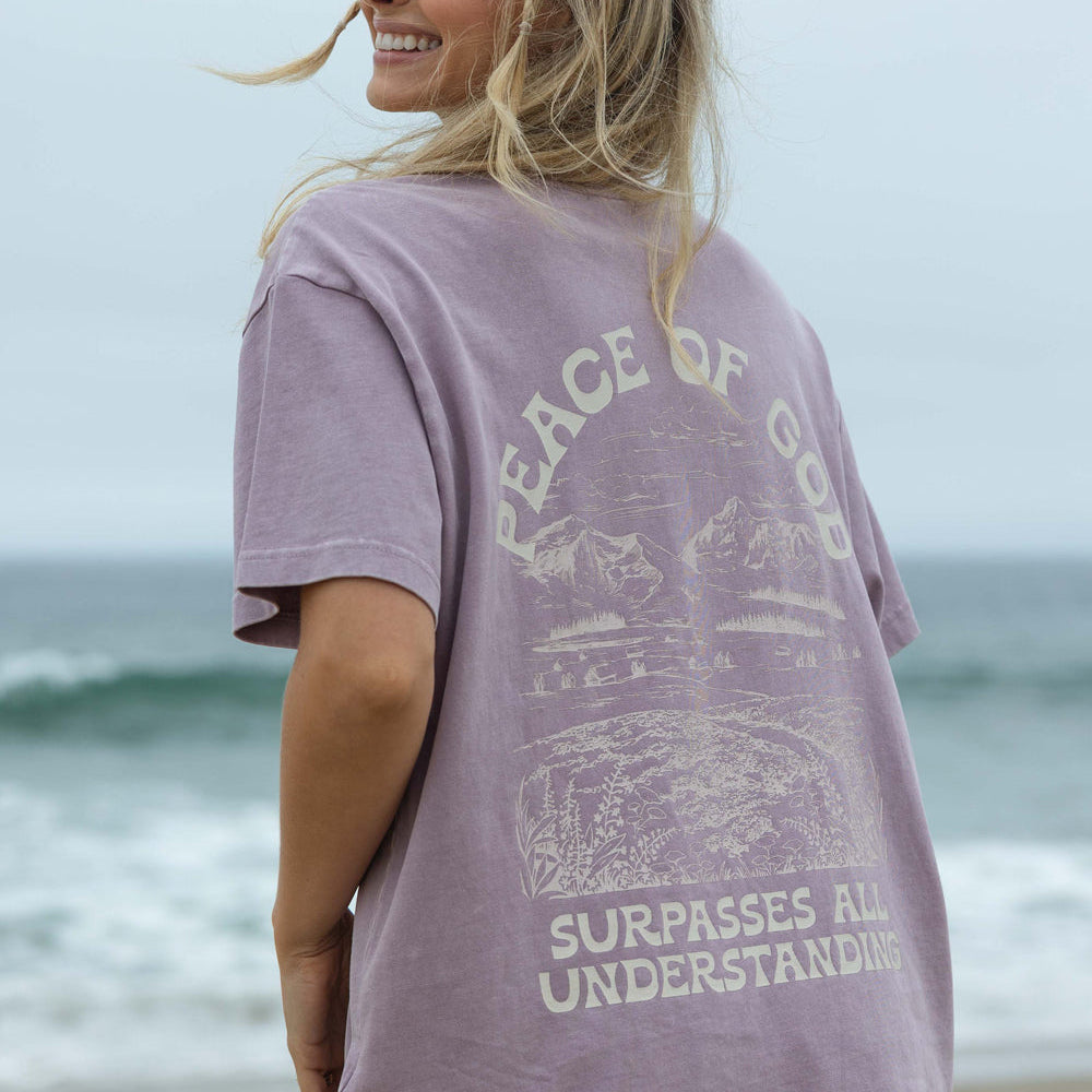 Woman wearing a purple t-shirt with a beach graphic and text on a beach background