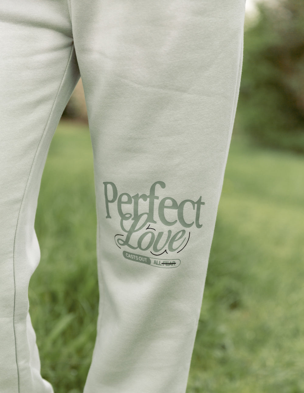 Light-colored pants with 'Perfect Love' text on a grassy background