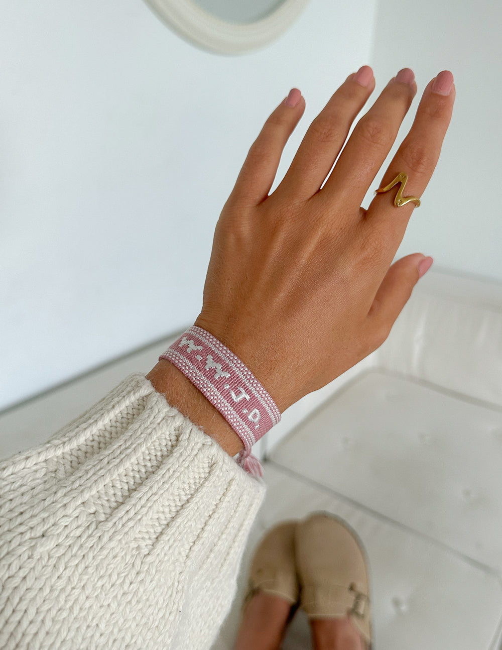 Dusty rose WWJD embroidered bracelet worn on a wrist with a cream knit sleeve