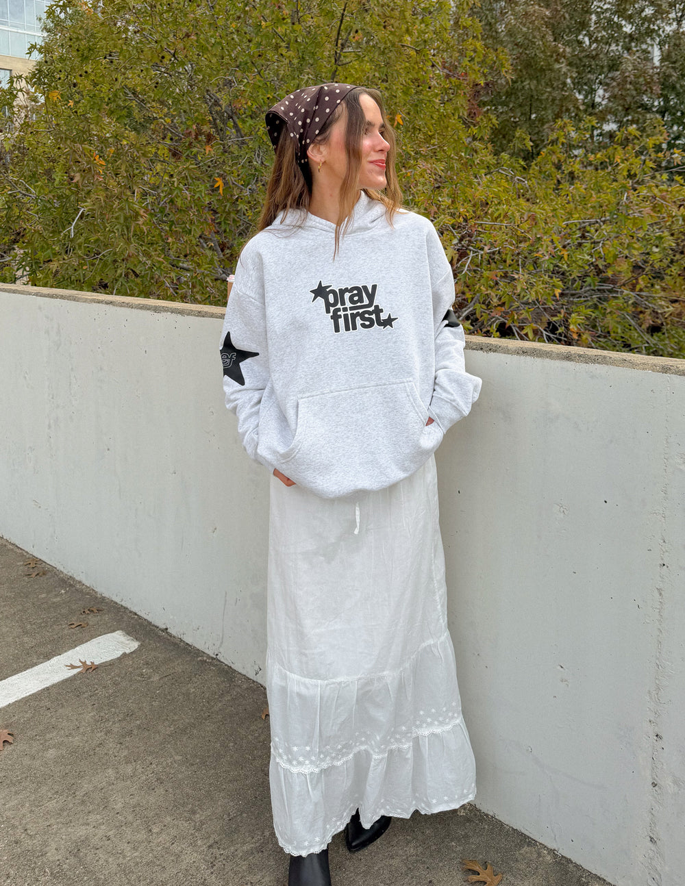 Woman wearing relaxed Pray First Heather Grey Hoodie with a long white skirt