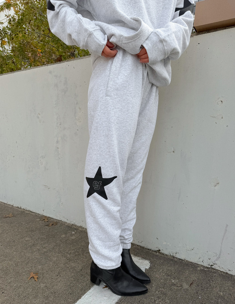 Close-up of the black star graphic on the leg of the Heather Grey Pray First sweatpants.