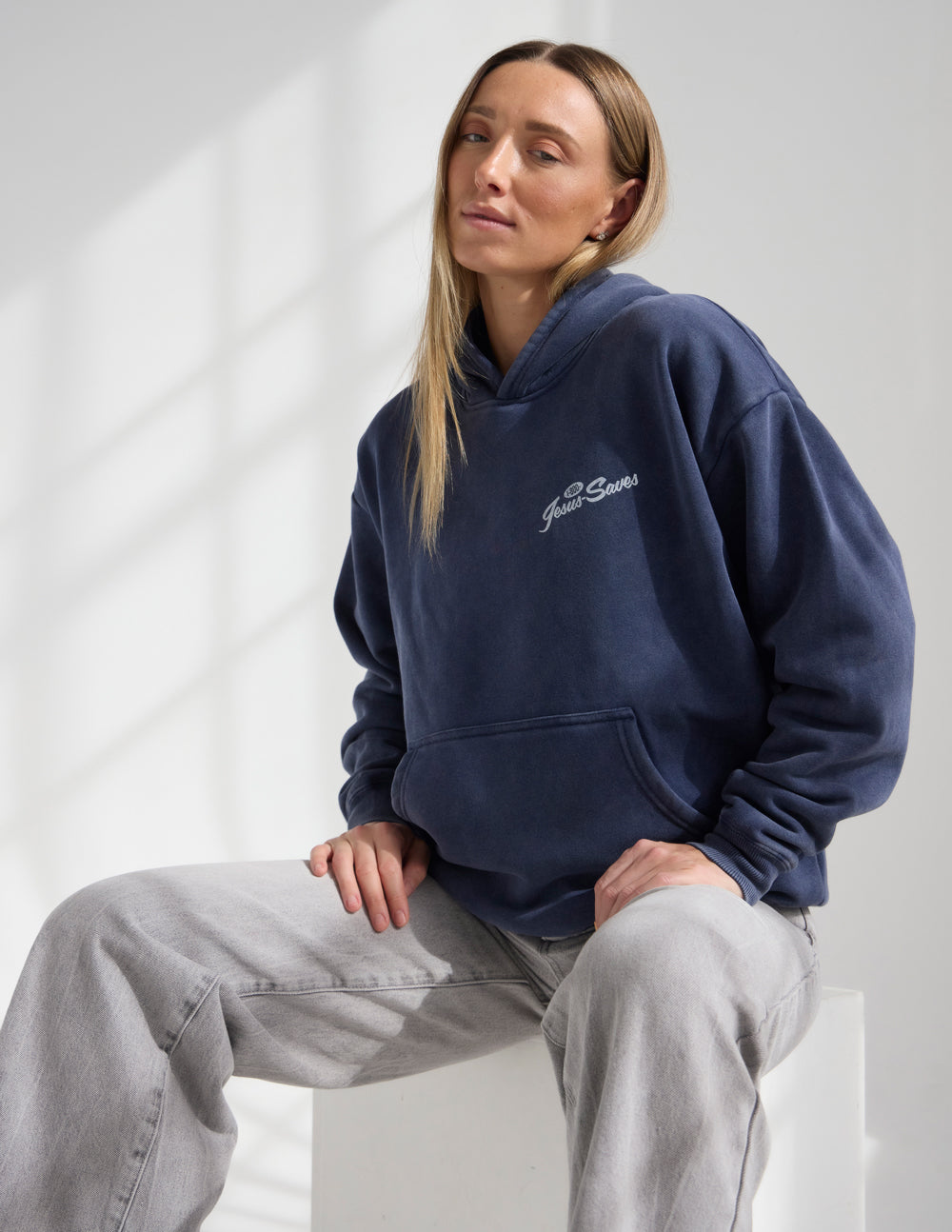 Model wearing Deep Navy Prayer Line unisex hoodie with grey pants
