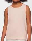 Young girl wearing a light pink sleeveless top against a white background
