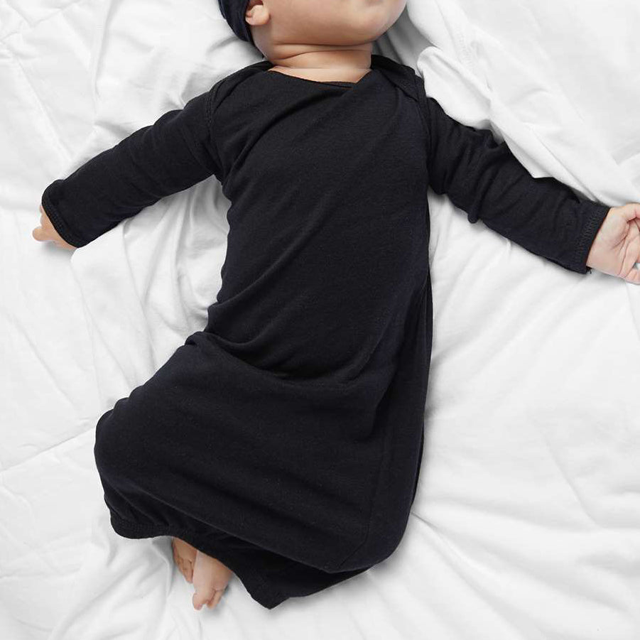 Baby wearing a black outfit and hat lying on a white surface