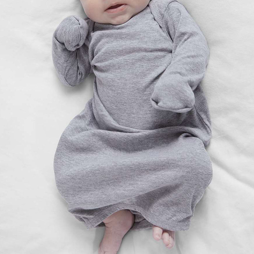 Baby in a gray onesie lying on a white blanket