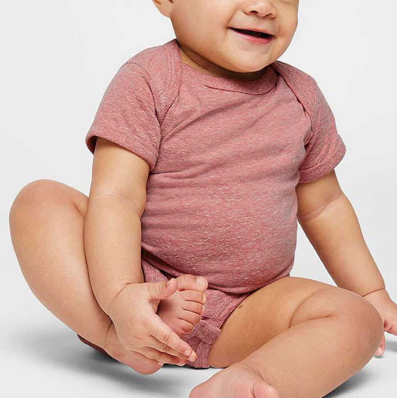 Baby wearing a pink onesie sitting on a white background