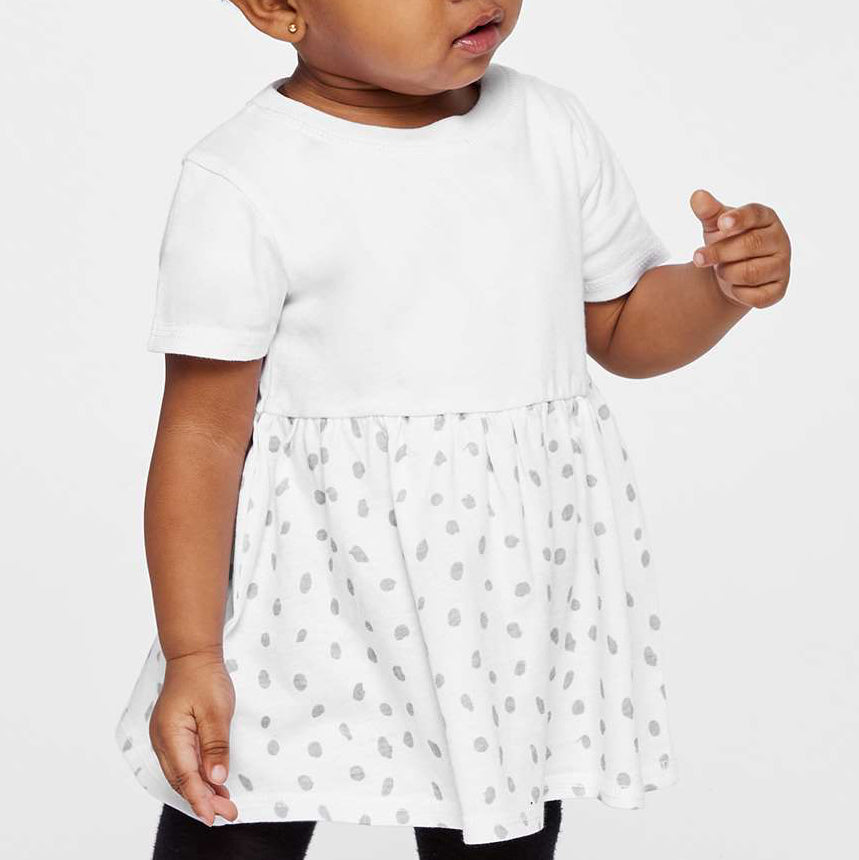 Child wearing a white dress with a polka dot skirt on a plain background