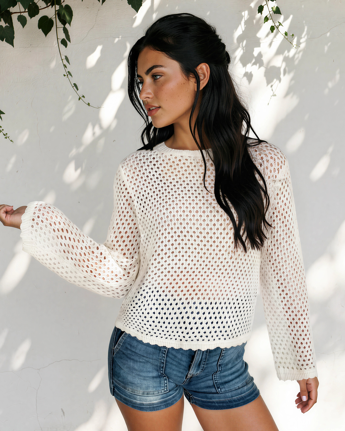 Side view of the white Felicity open-knit top showing its relaxed fit and flared sleeve cuffs.