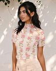 Close-up of the Millie mesh top featuring pink flowers, green foliage, a mock neckline, and short sleeves.