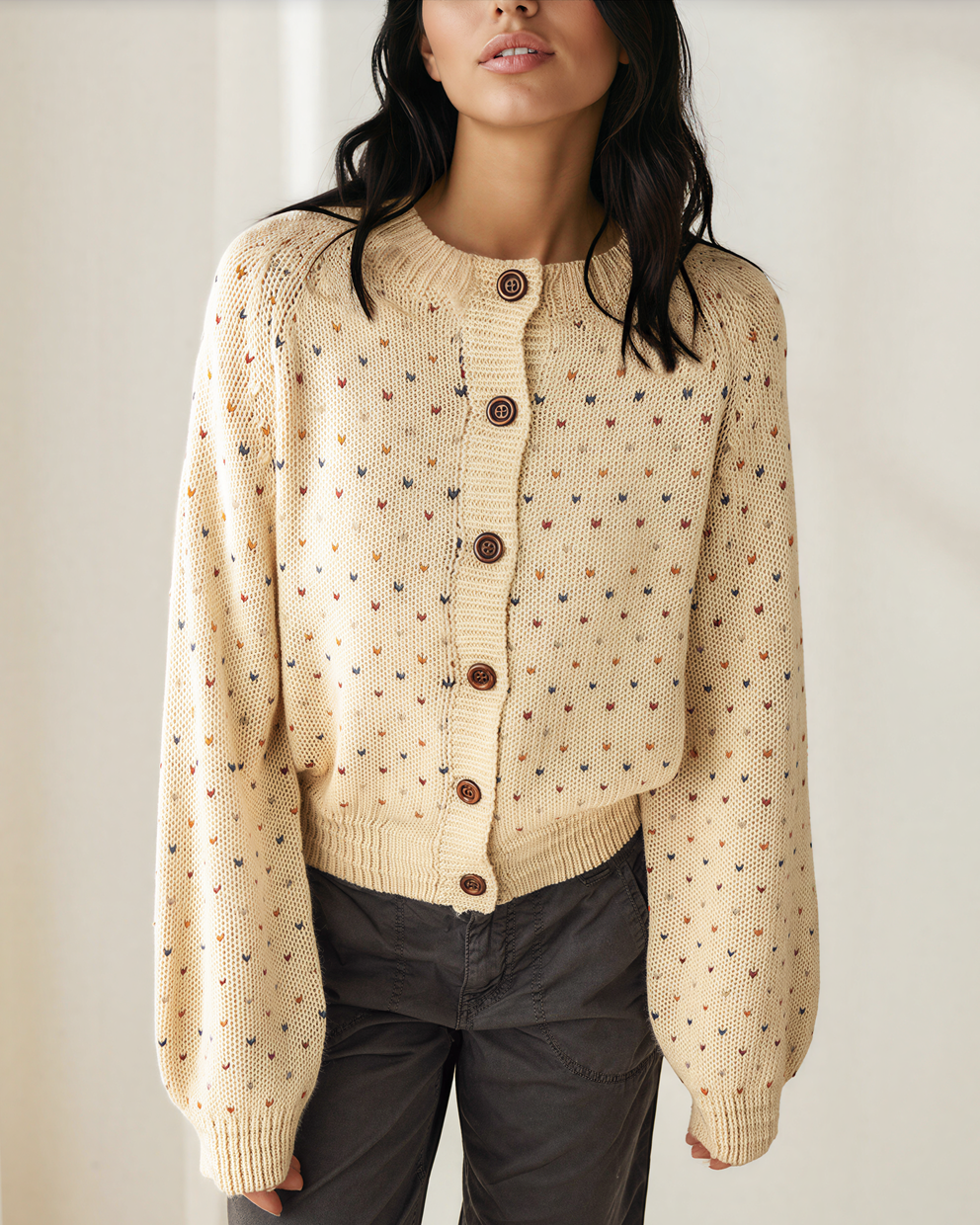 Front view of the cream Kaia geometric knit cardigan with long sleeves and ribbed cuffs, styled with dark pants.