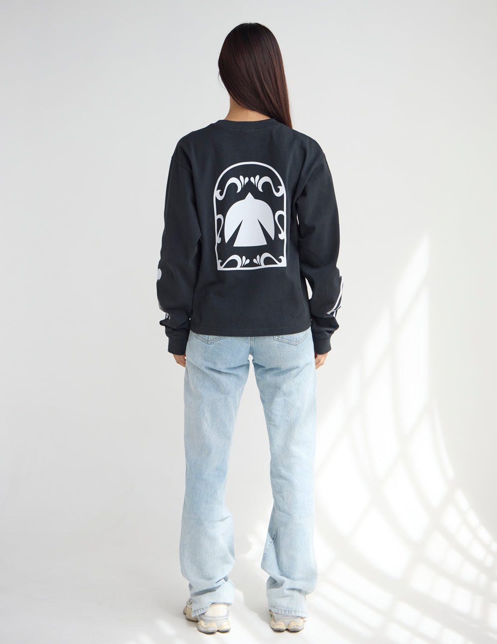 Back view of the Spirit Is Moving black tee with a large white dove graphic, styled with light-wash jeans