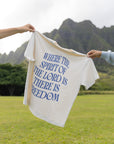 Spirit of the Lord Nimbus Cloud T-shirt held outdoors, showing large blue scripture-inspired back lettering.
