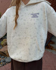 Close-up of the ivory Talk to God hoodie showing the wildflower print, chest lettering, and kangaroo pocket