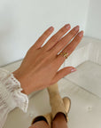 Textured Wrapped Cross Gold-Tone Ring worn with a white ruffled sleeve indoors