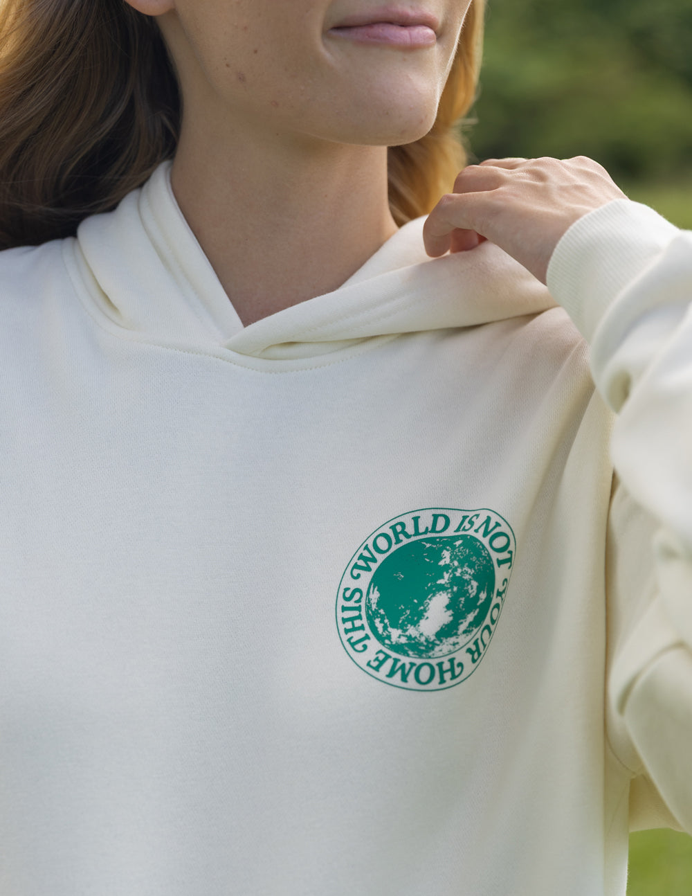 Close-up of the Egret hoodie’s small green chest graphic and hood neckline.