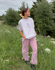 Model standing among wildflowers wearing the oversized Petal Purple Try With God Unisex Tee