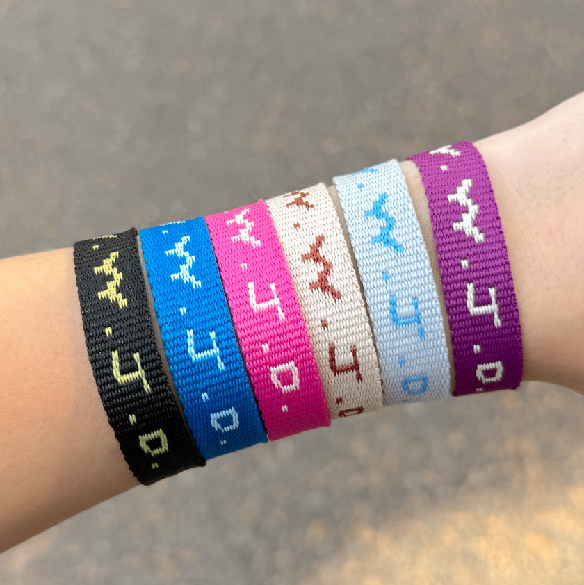 Wrist wearing multiple colorful wristbands with text on a blurred background