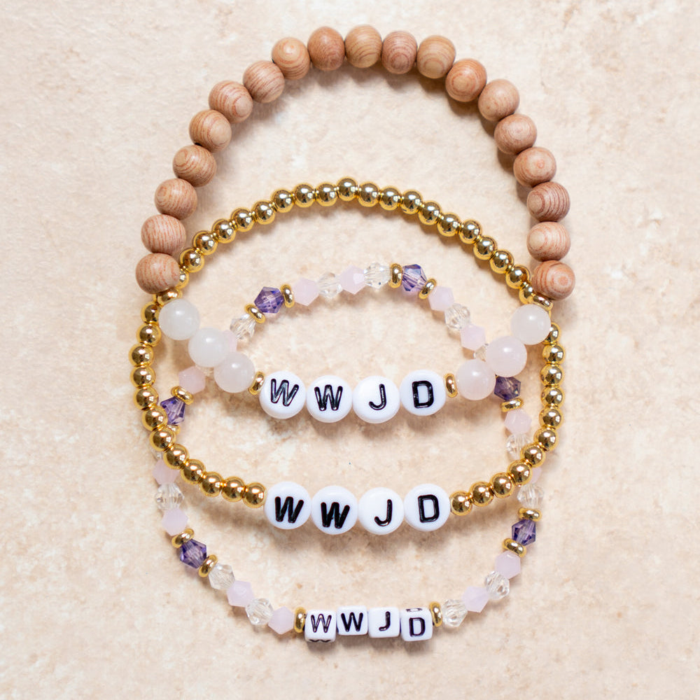 Set of beaded bracelets with 'WWJD' charms on a beige background